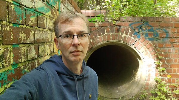 Mark Ridyard stands in front of a sewage outfall pipe