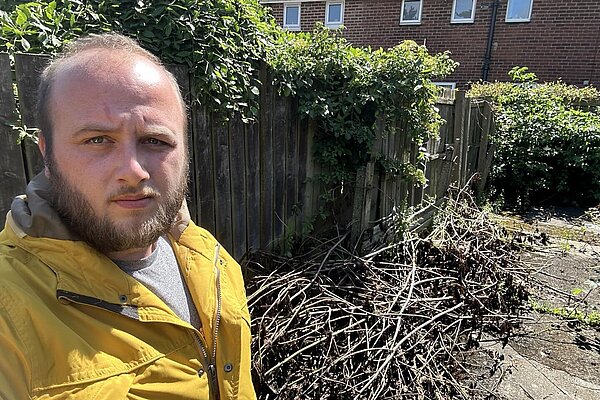 Rob pictured by bushes and rubbish