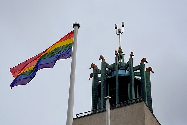 Pride flag flying on flagpole in foreground; tower of Newcastle Civic Centre in background