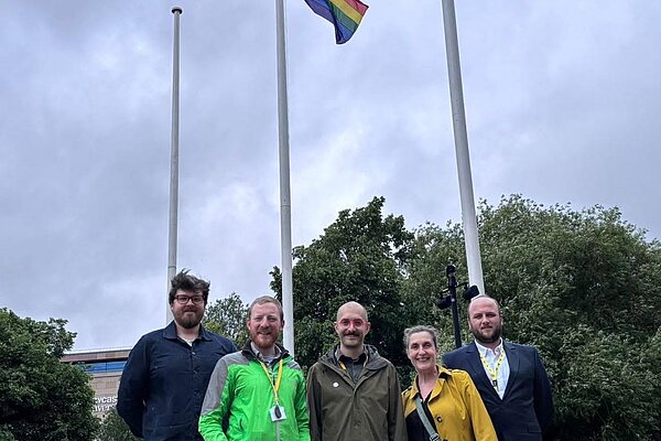 Liberal Democrat councillors James Coles, Colin Ferguson, Owen Burbidge, Deborah Burns and Rob Austin stood before Pride flag flying at Newcastle Civic Centre