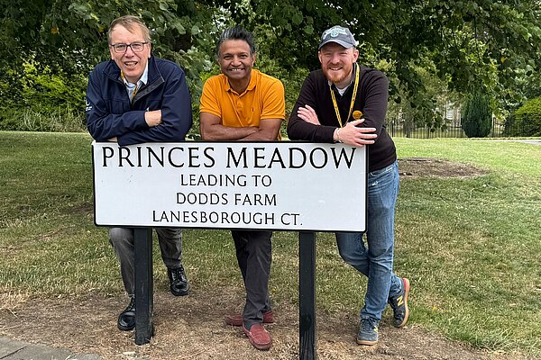 Tom, Colin and Tahir leaning on the Princes Meadow road sign
