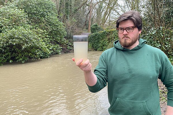 James holding a glass of dirty Ouseburn water