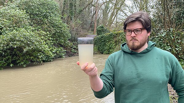 James Coles holds a glass of dirty Ouseburn water for inspection