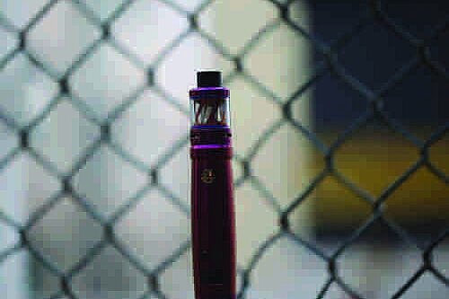 Vape in front of a chain link fence